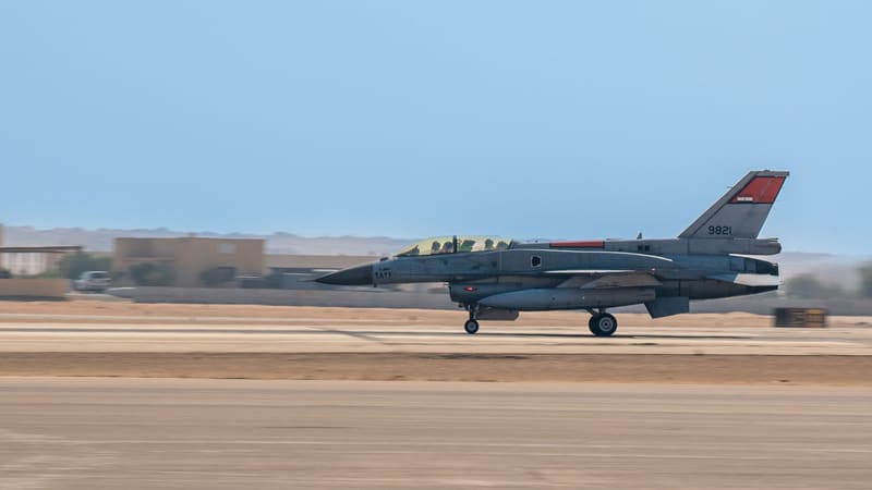 Two-seat Egyptian Air Force F-16 with a red tail flash, Egyptian flag and serial 9821 rolling along a desert runway
